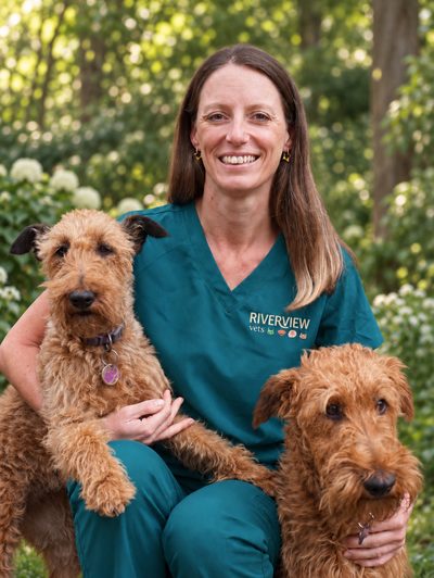 Susannah Covacic in Riverview scrubs, sitting outdoors with her two Irish terriers